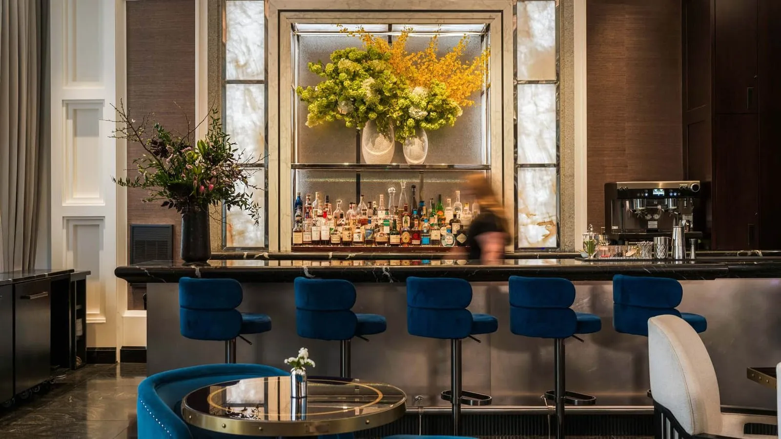 Blue bar stools and a floral arrangement behind the bar at Trifecta